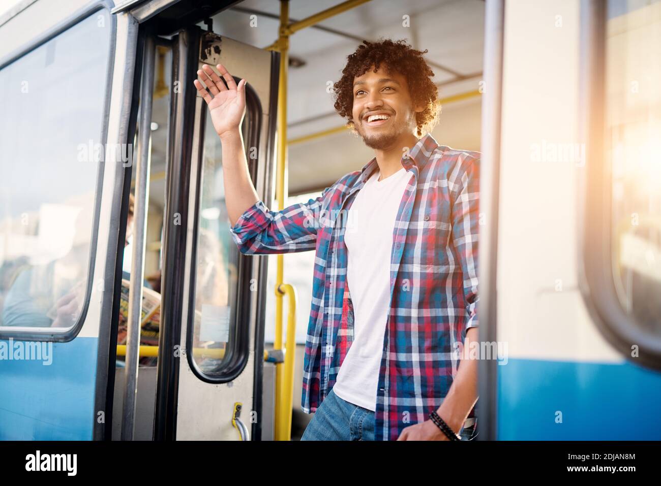 Jeune homme joyeux et joyeux agite avec un sourire sur son visage lorsqu'il quitte le bus. Banque D'Images