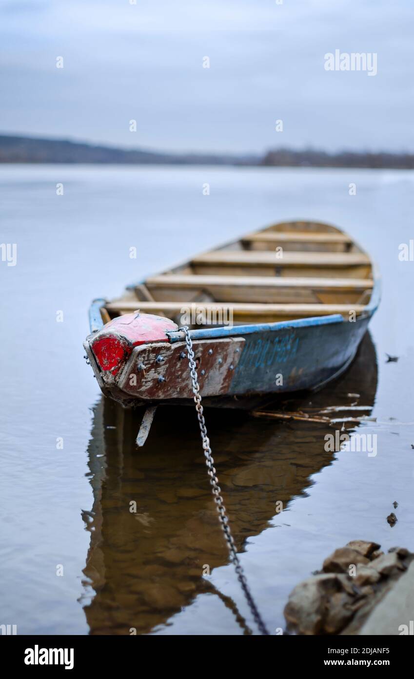 Bateau bleu en bois amarré avec une chaîne le long de la côte sur l'eau calme Banque D'Images