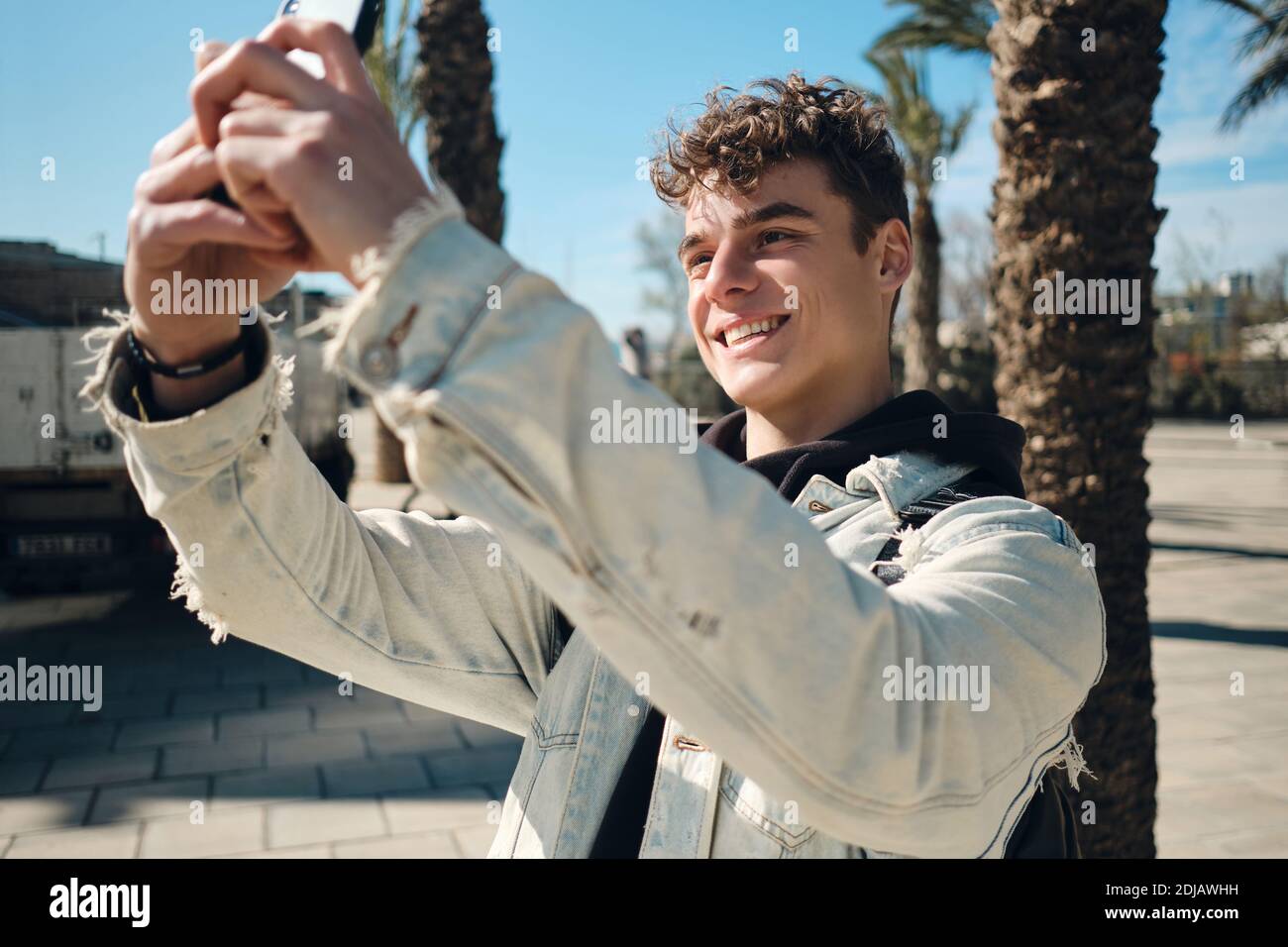 Portrait d'un homme attrayant prenant des photos avec joie sur un smartphone en extérieur Banque D'Images