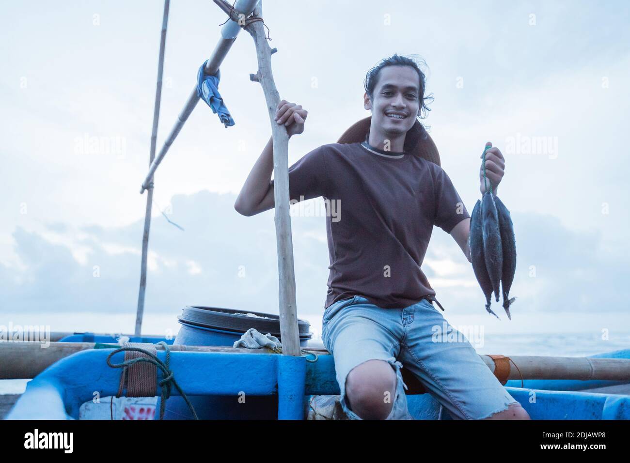 Gros plan d'un jeune pêcheur montrant son poisson capturé Banque D'Images