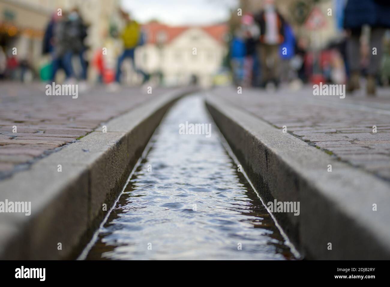 La piste d'eau Freiburg Bächle en gros plan et sélective vue au niveau du sol avec des piétons qui marchent dans la rue Banque D'Images