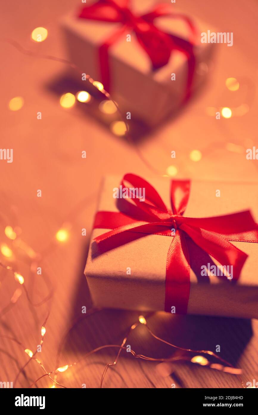 Boîte cadeau de Noël avec rubans rouges et lumières de fête floues Banque D'Images