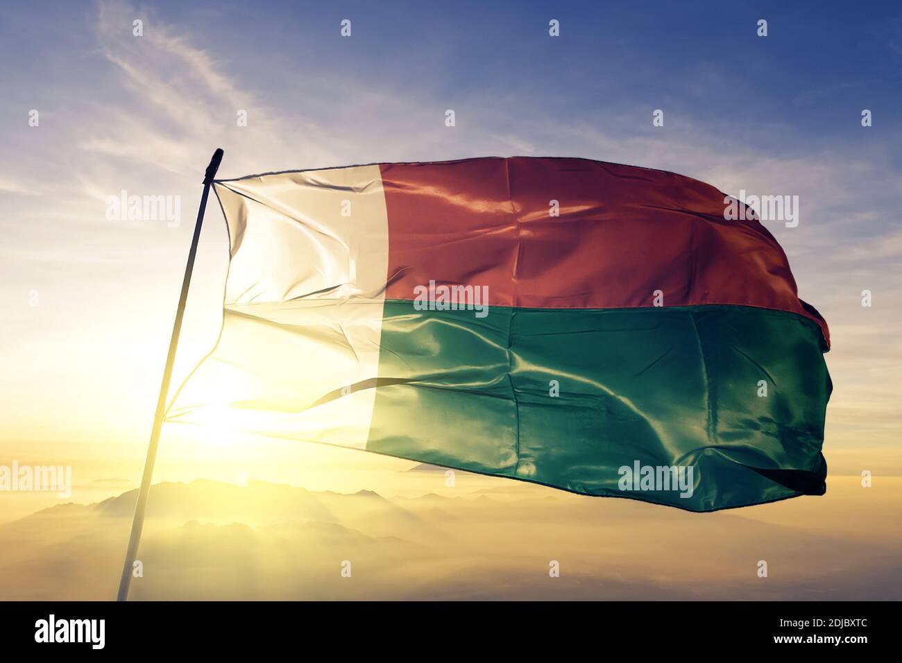 Drapeau de Madagascar qui agite sur le brouillard du lever du soleil Banque D'Images