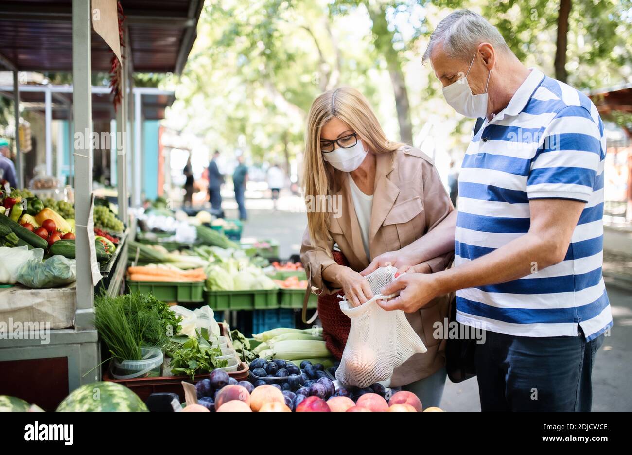 Portrait d'un couple senior faisant du shopping sur le marché extérieur de la ville, concept de coronavirus. Banque D'Images