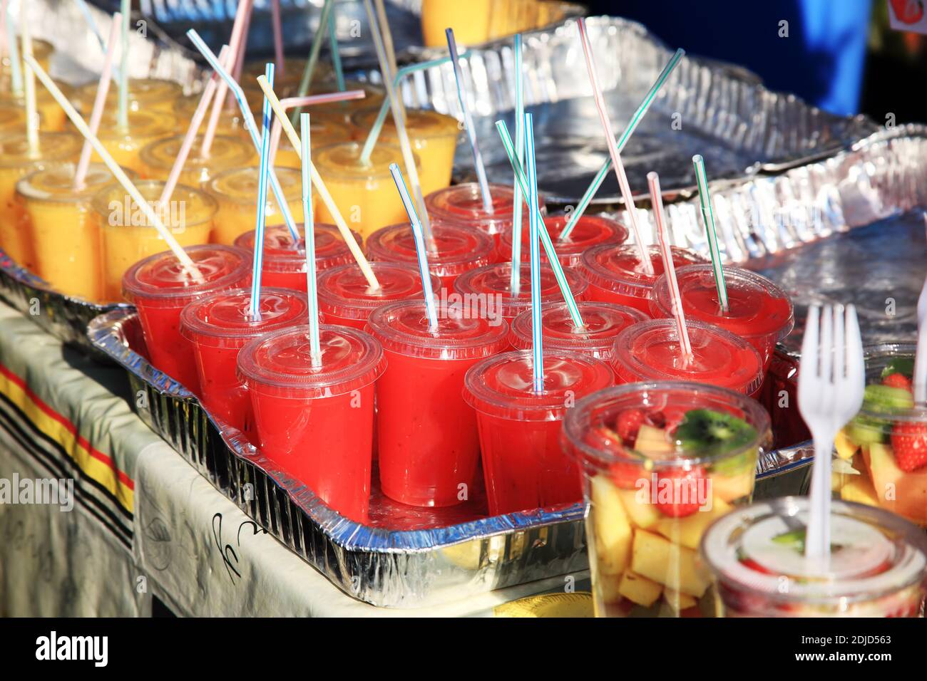 Plateaux en papier d'aluminium contenant des milkshakes aux fraises et aux bananes dans des verres en plastique et des pailles insérées qui sont un environnement problème dû à son Banque D'Images
