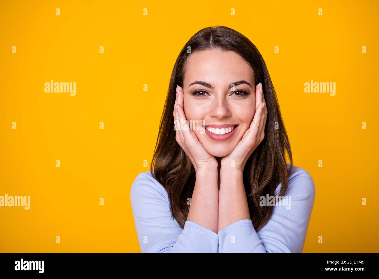 Coseup photo de belle dame gaie bonne humeur bras sur pommettes émotions surjoyeuses sourire plein de charme apparence porter chemise décontractée isolé Banque D'Images