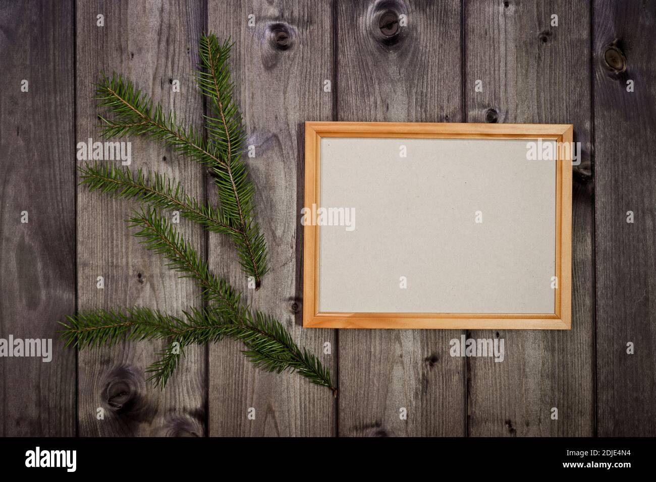 Maquette cadre en bois vide et branche de sapin sur fond de mur en pin foncé, montrer du texte ou du produit. Thème de Noël. Banque D'Images