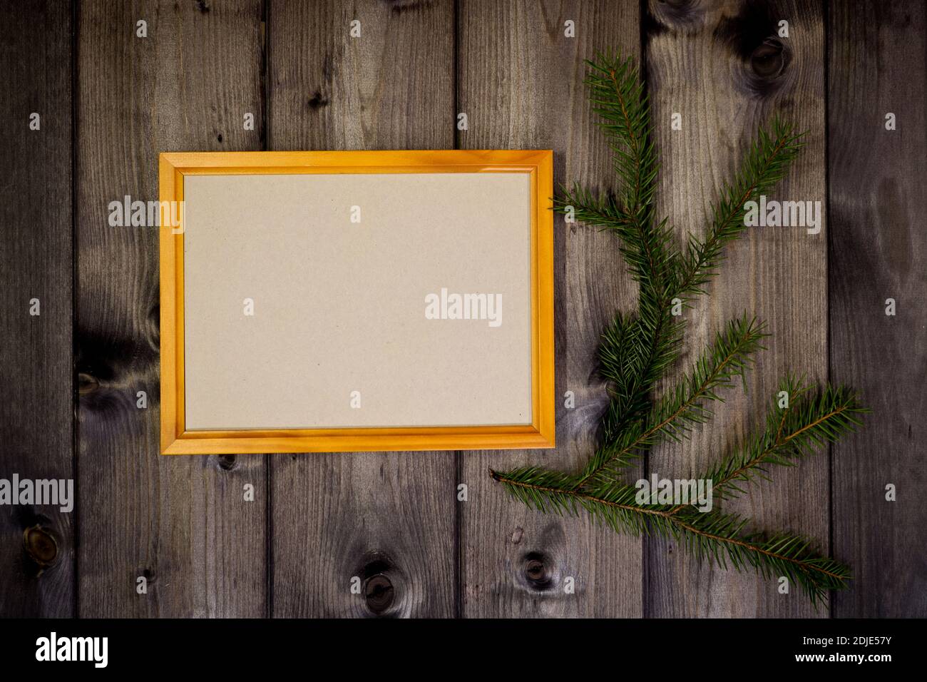 Maquette cadre en bois vide et branche de sapin sur fond de mur en pin foncé, montrer du texte ou du produit. Thème de Noël. Banque D'Images
