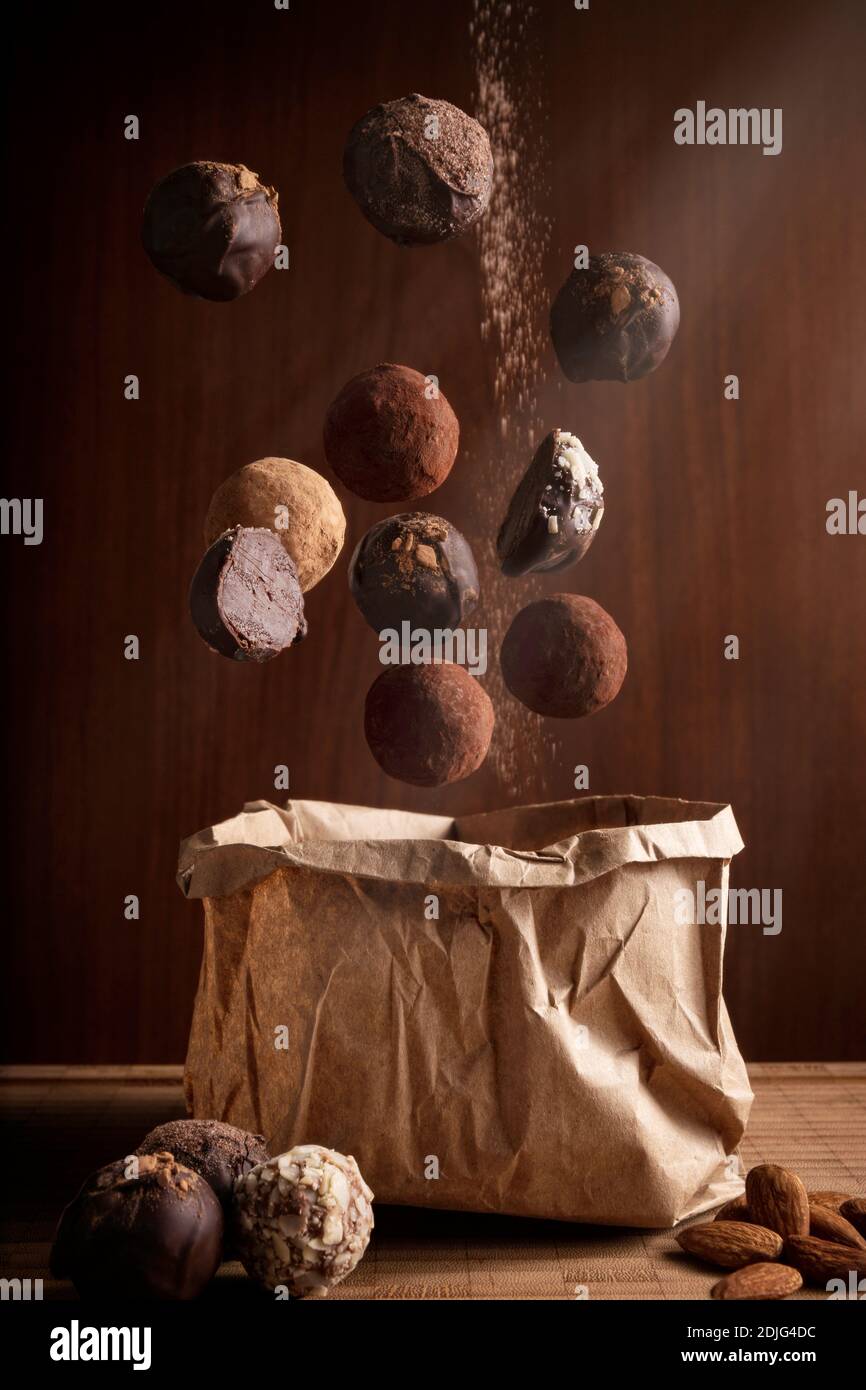 composition photographique créative de délicieux truffes au chocolat flottant et et sac de papier artisanal sur fond en bois Banque D'Images