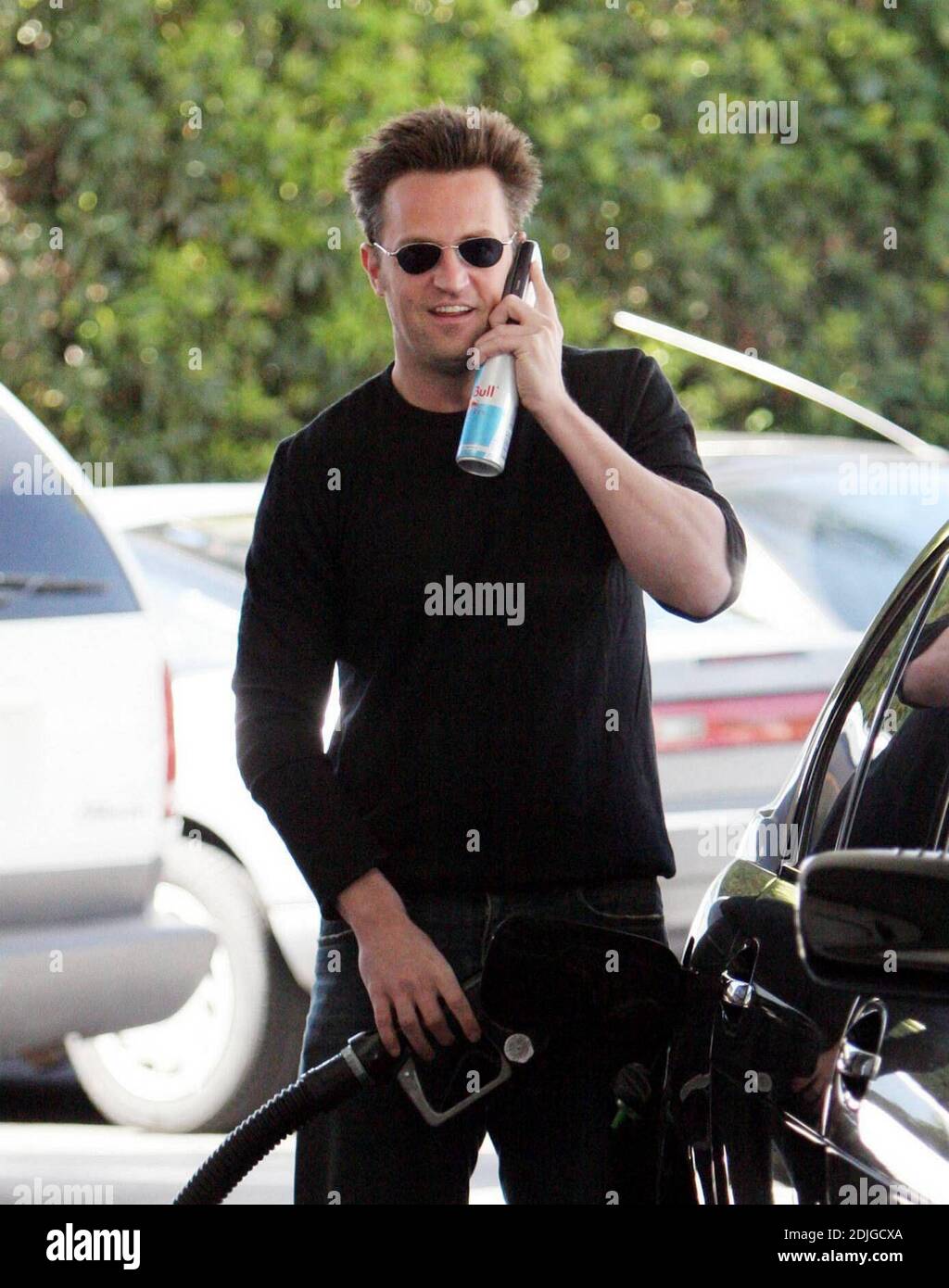 Exclusif !! Matthew Perry mutli tâches à Beverly Hills, ca. L'acteur a bavardé sur son téléphone portable tout en remplissant son réservoir de gaz et en se tenant à une bouteille de la boisson énergétique, Diet Red Bull 03/02/06 Banque D'Images