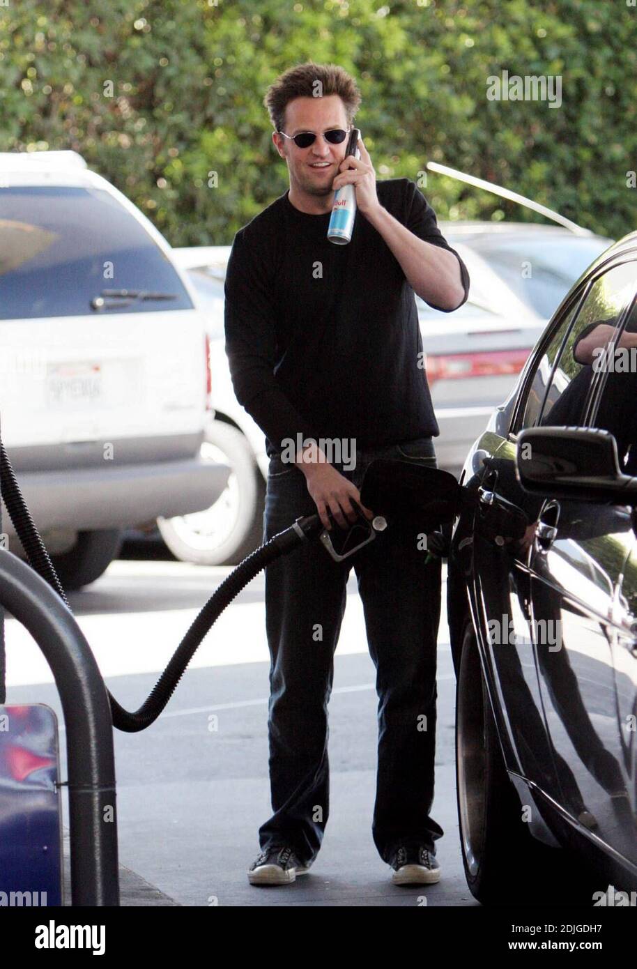 Exclusif !! Matthew Perry mutli tâches à Beverly Hills, ca. L'acteur a bavardé sur son téléphone portable tout en remplissant son réservoir de gaz et en se tenant à une bouteille de la boisson énergétique, Diet Red Bull 03/02/06 Banque D'Images