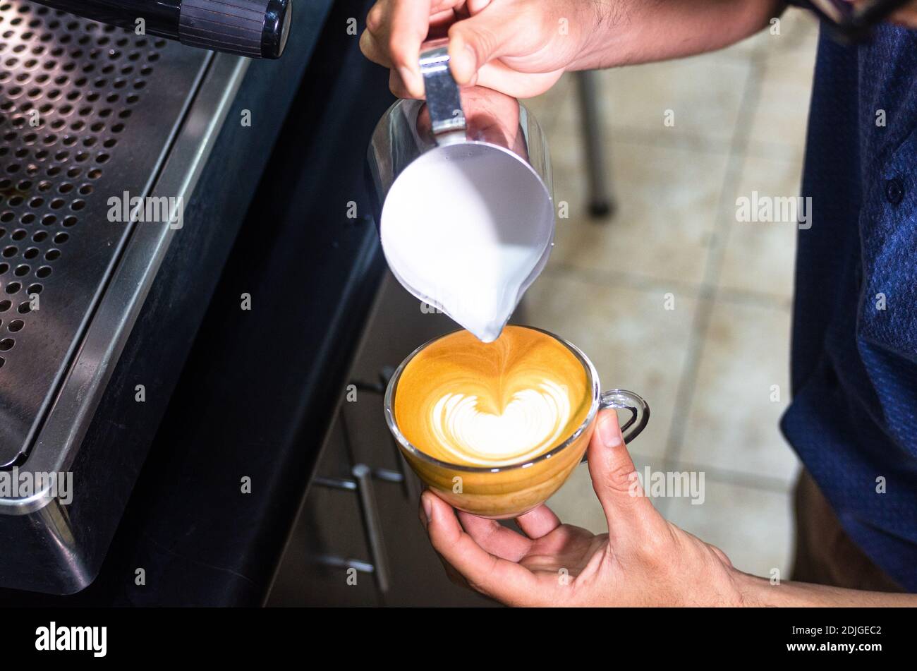 Main du barista qui prépare du café au Latte ou au Cappuccino, verse du lait pour préparer des latte Banque D'Images