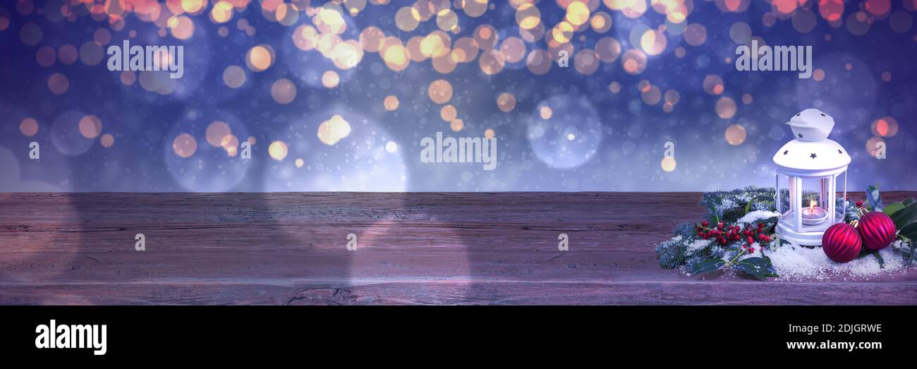 Lanterne de Noël blanche sur une table en bois devant un arrière-plan bleu foncé avec des lumières floues. Banque D'Images