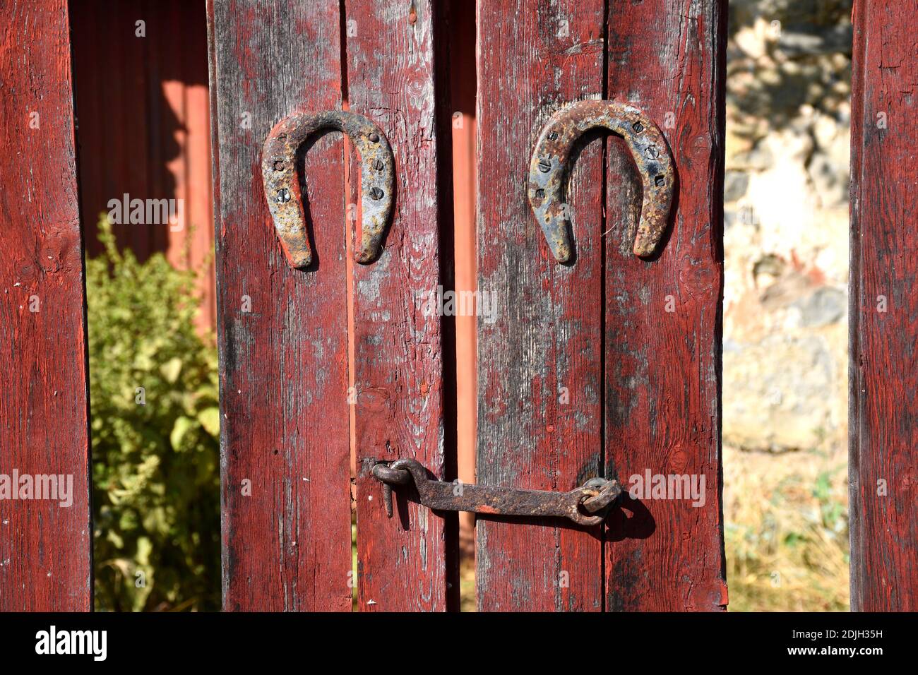 Porte en bois rouge avec serrure et deux fers à cheval cloués. Banque D'Images