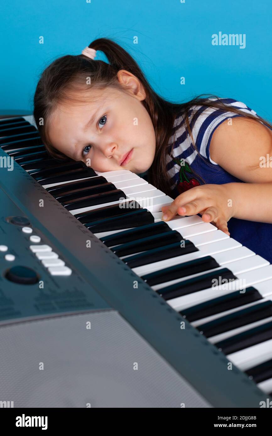 gros plan d'une fille qui pleure avec sa tête sur les touches du synthétiseur, contrarié qu'elle ne puisse pas apprendre une mélodie complexe Banque D'Images