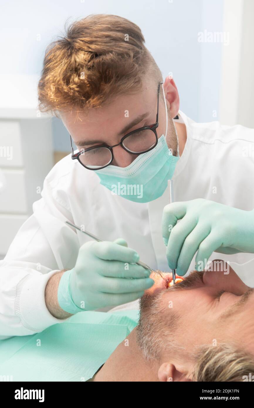 Dentiste donnant un traitement dentaire sur un patient Banque D'Images