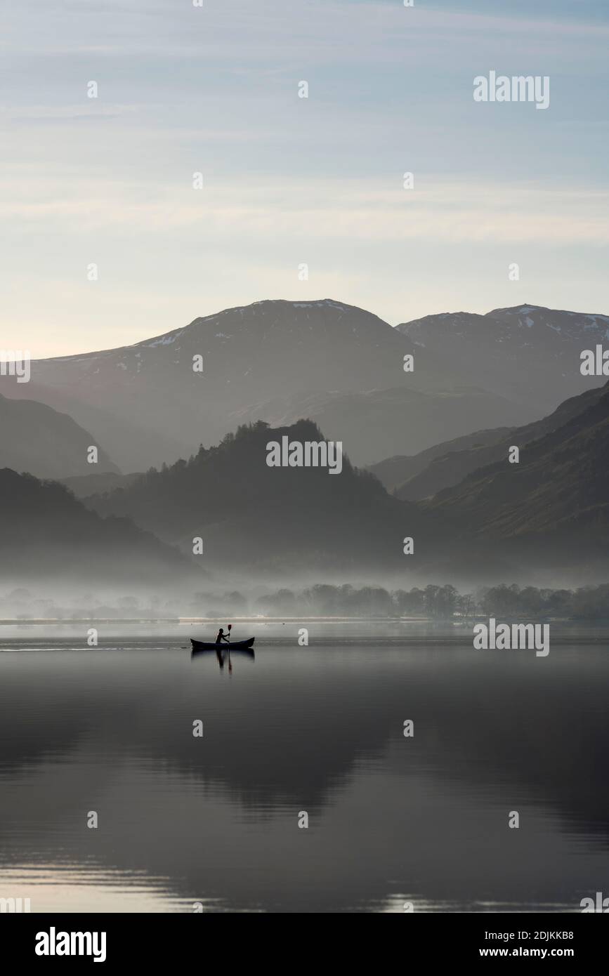 Le matin, le canoéiste s'exerce sur Derwentwater lors d'une belle journée de vignerons, avec les coquillages reflétés dans les eaux calmes. Lake District, Cumbria, Angleterre Banque D'Images