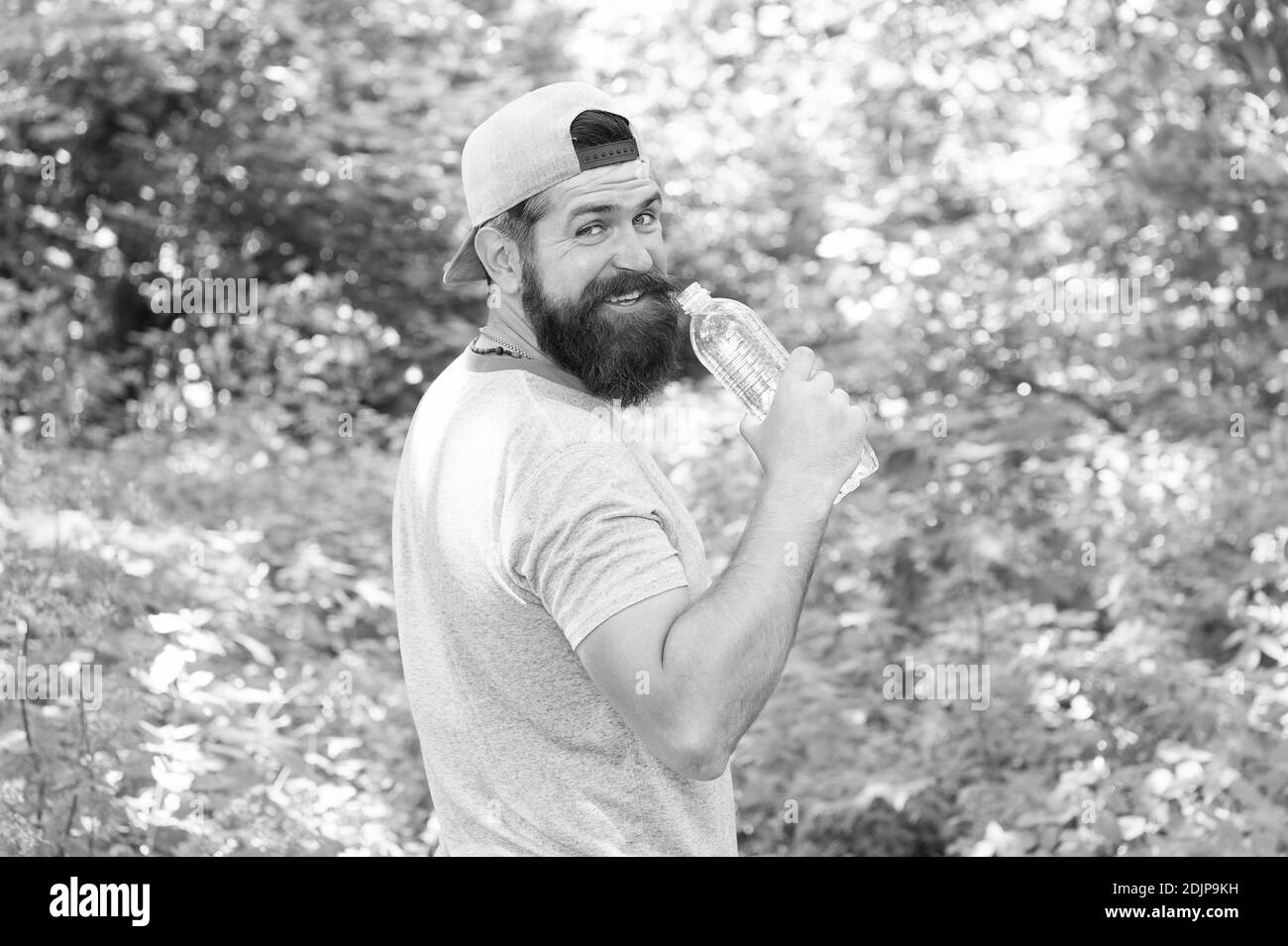 Hydrate ou mourir. Hipster brutal en forêt. Découvrez de nouveaux endroits. Temps pour pique-niquer. Guy boit de l'eau. Homme barbu en cap. Vacances d'été en camping. Homme randonnée. Homme envie d'avoir soif. Banque D'Images