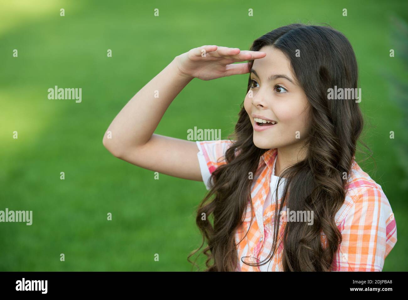 Pute fille inspirée avec de longs cheveux ondulés regarder dans la distance  en gardant la main sur le front herbe verte ensoleillé été plein air, futur  Photo Stock - Alamy