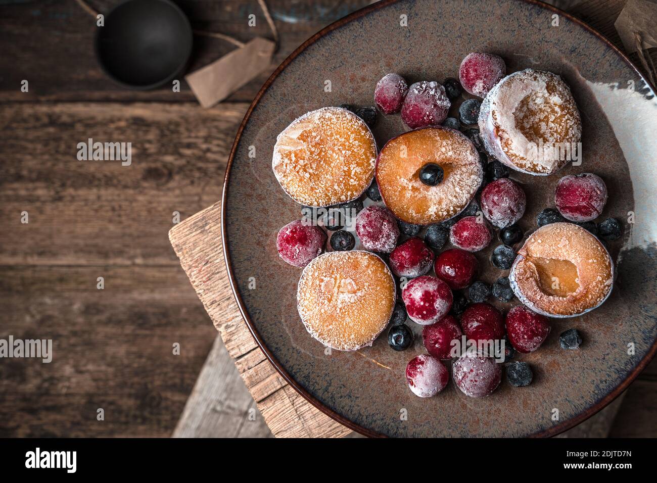 Baies et prunes surgelées sur une assiette brune. Banque D'Images