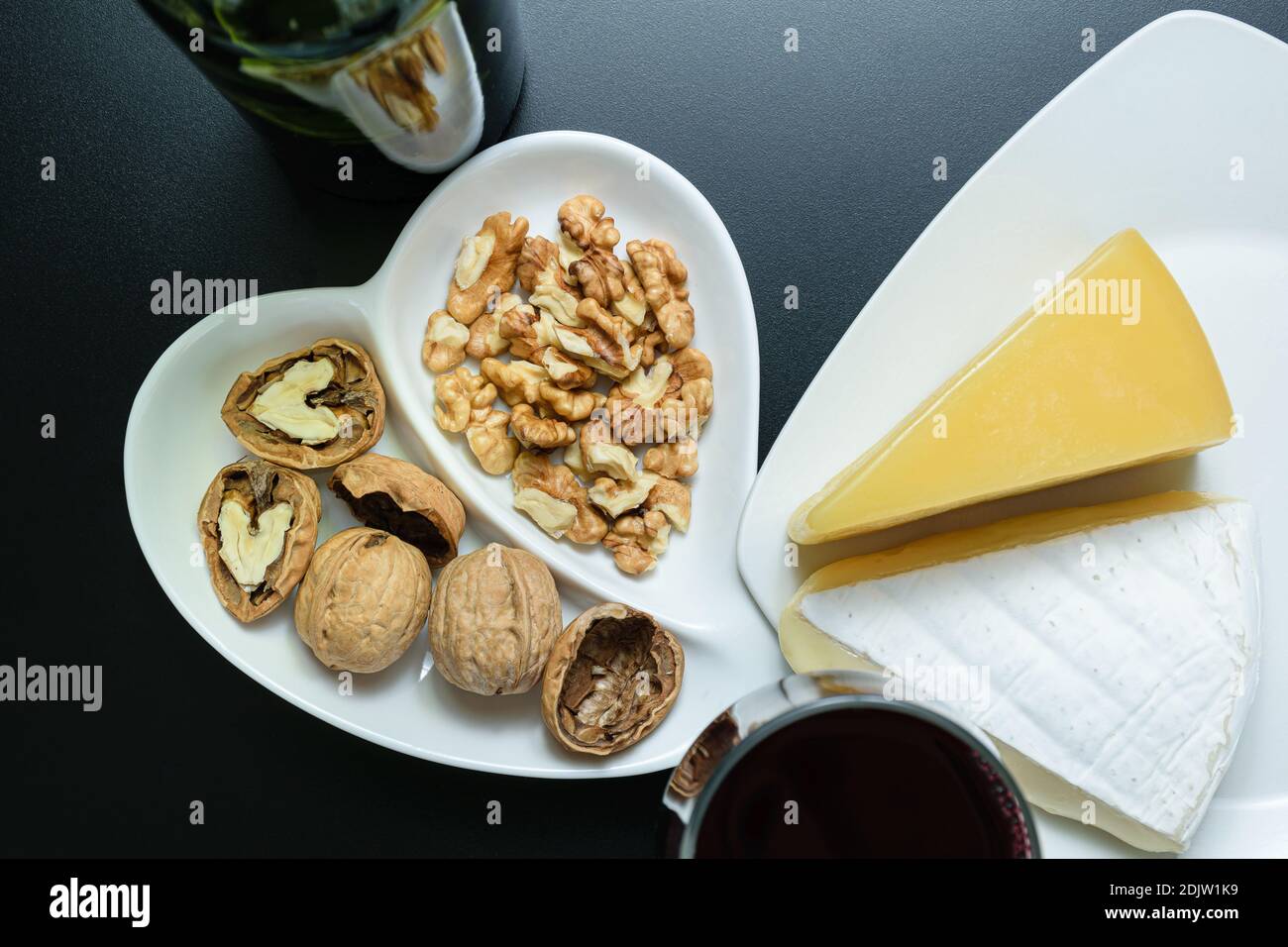 Portion de noix au parmesan et à la brie, verre et bouteille de vin rouge (vue de dessus). Banque D'Images