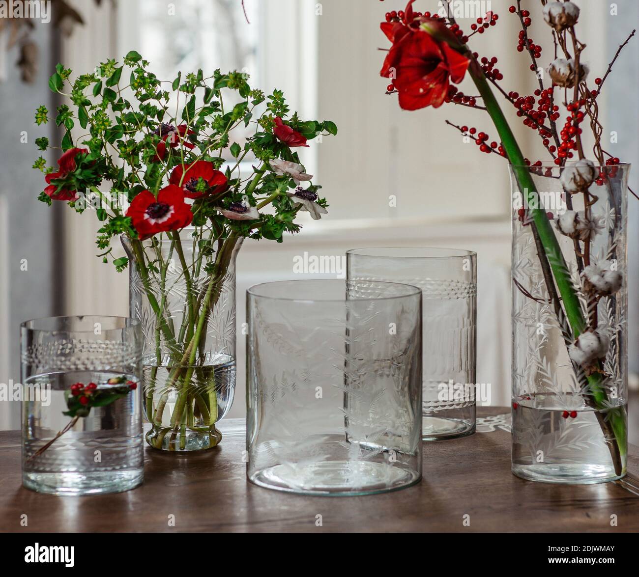 Un cliché sélectif de fleurs dans des vases en verre eau et vases en verre vides sur la table Banque D'Images