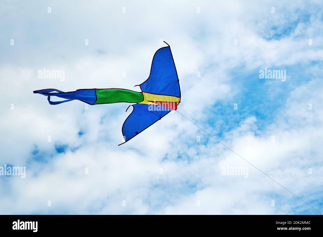 Grand cerf-volant coloré dans le ciel bleu avec des nuages blancs. Jouets et jeux pour enfants. Activités de loisirs en plein air Banque D'Images