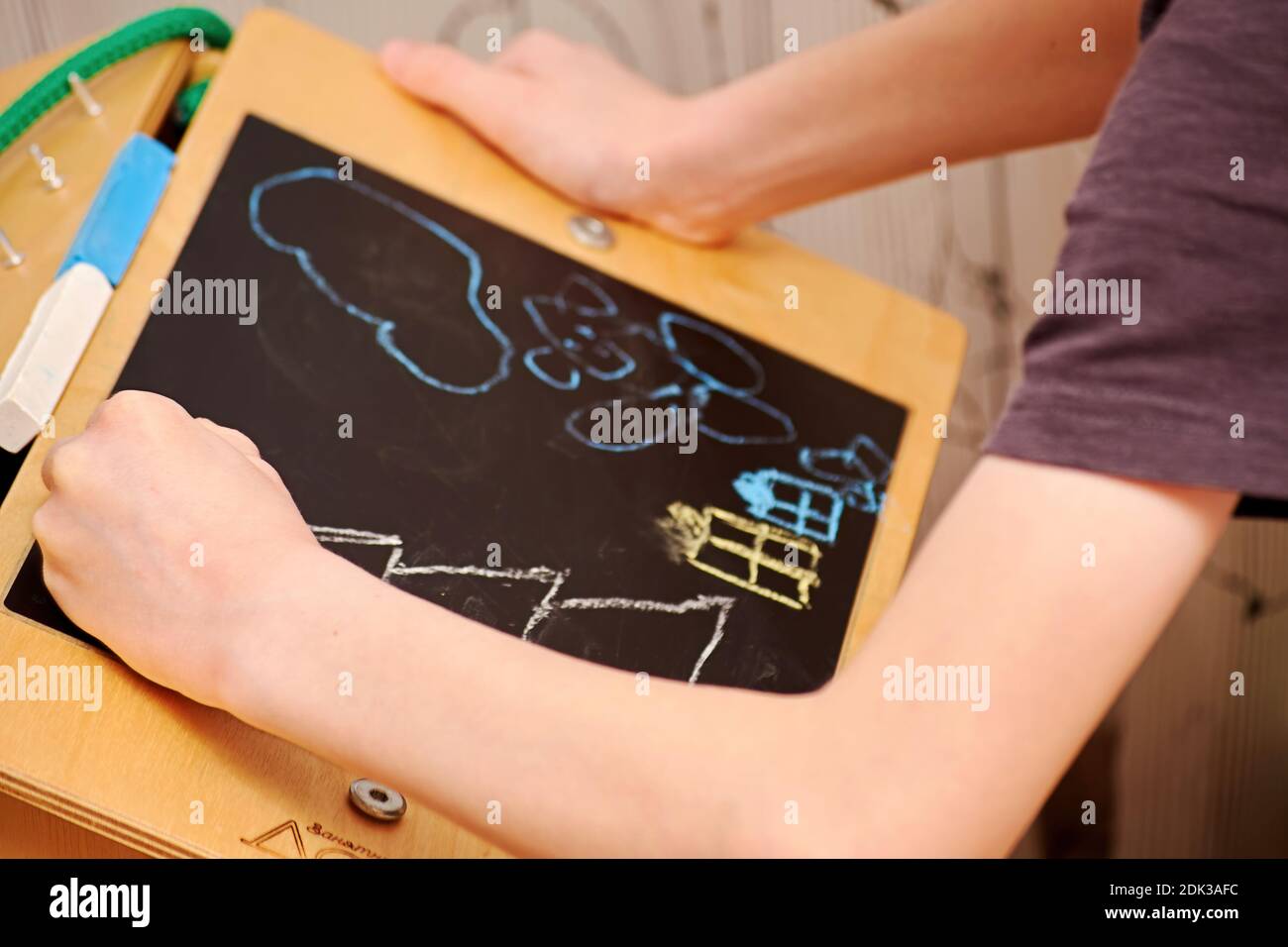 Un garçon dessine une scène de Noël sur le tableau noir de la maternelle. Vacances et hobby pour enfants Banque D'Images