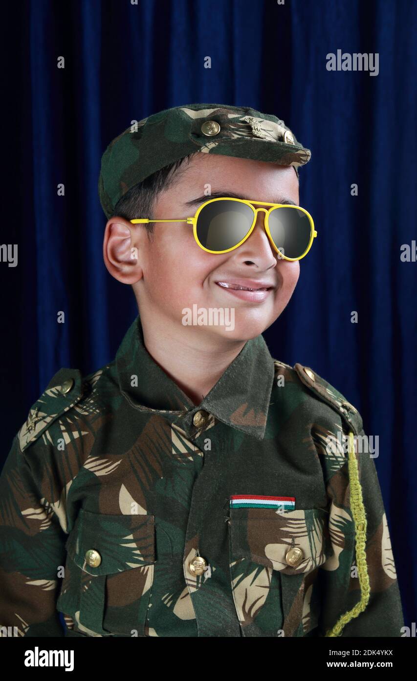 Sourire garçon dans l'uniforme de l'armée et lunettes de soleil debout  contre le rideau Photo Stock - Alamy