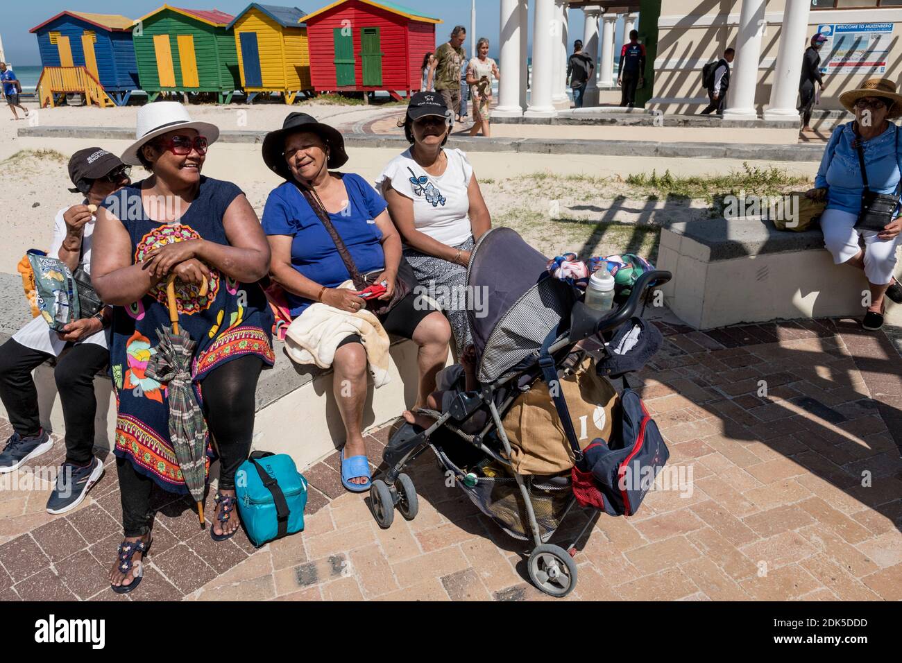 Un groupe social communautaire de femmes sur une sortie à Surferss' Corner, plage de Muizenberg, le Cap, Afrique du Sud. Cabines de plage peintes en bois en arrière-plan. Banque D'Images