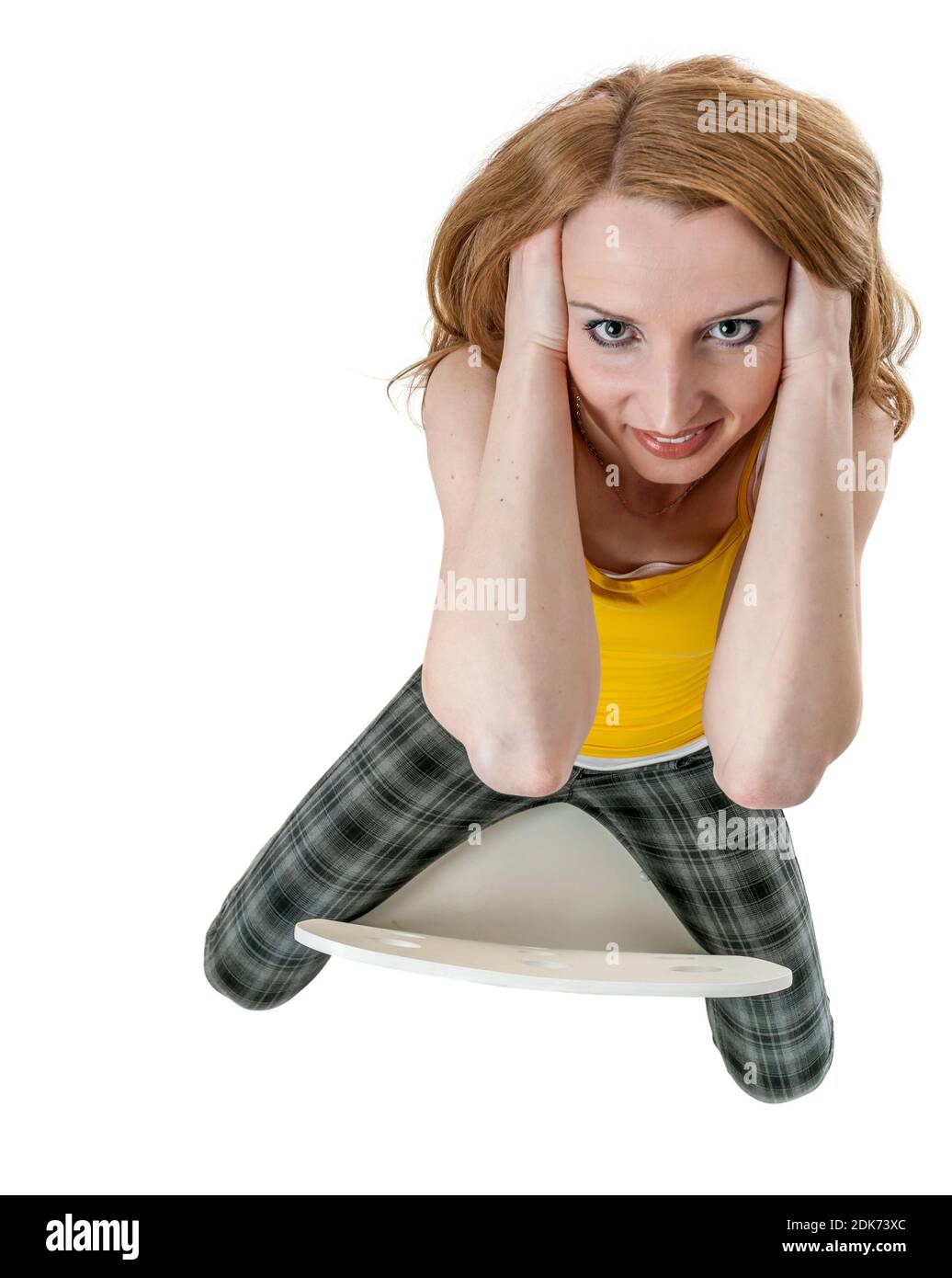 Grand angle très haute vue sur toute la longueur d'une jeune femme blonde assise sur une chaise avec les mains à gauche et à droite dans ses cheveux regardant amicaux. Banque D'Images