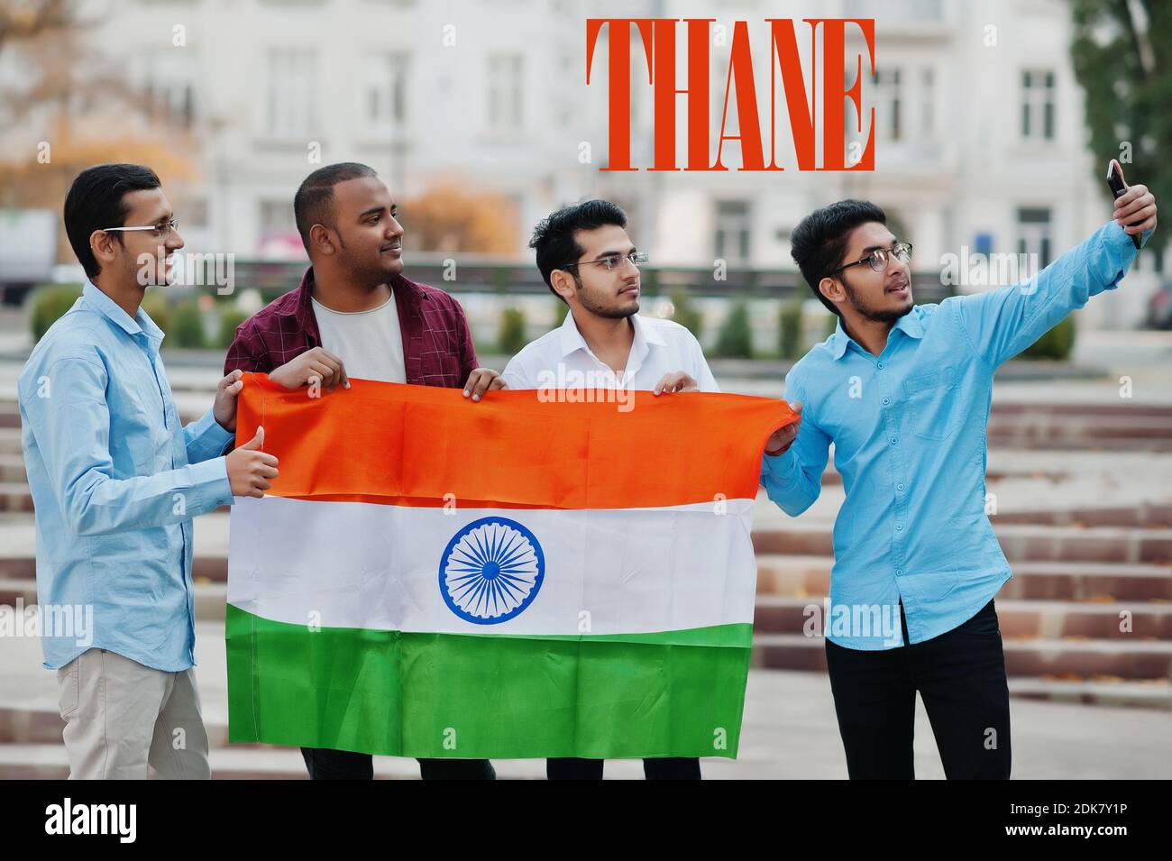 Inscription de la ville de Thane. Groupe de quatre amis indiens masculins avec drapeau indien faisant selfie sur téléphone mobile. Concept des plus grandes villes de l'Inde. Banque D'Images