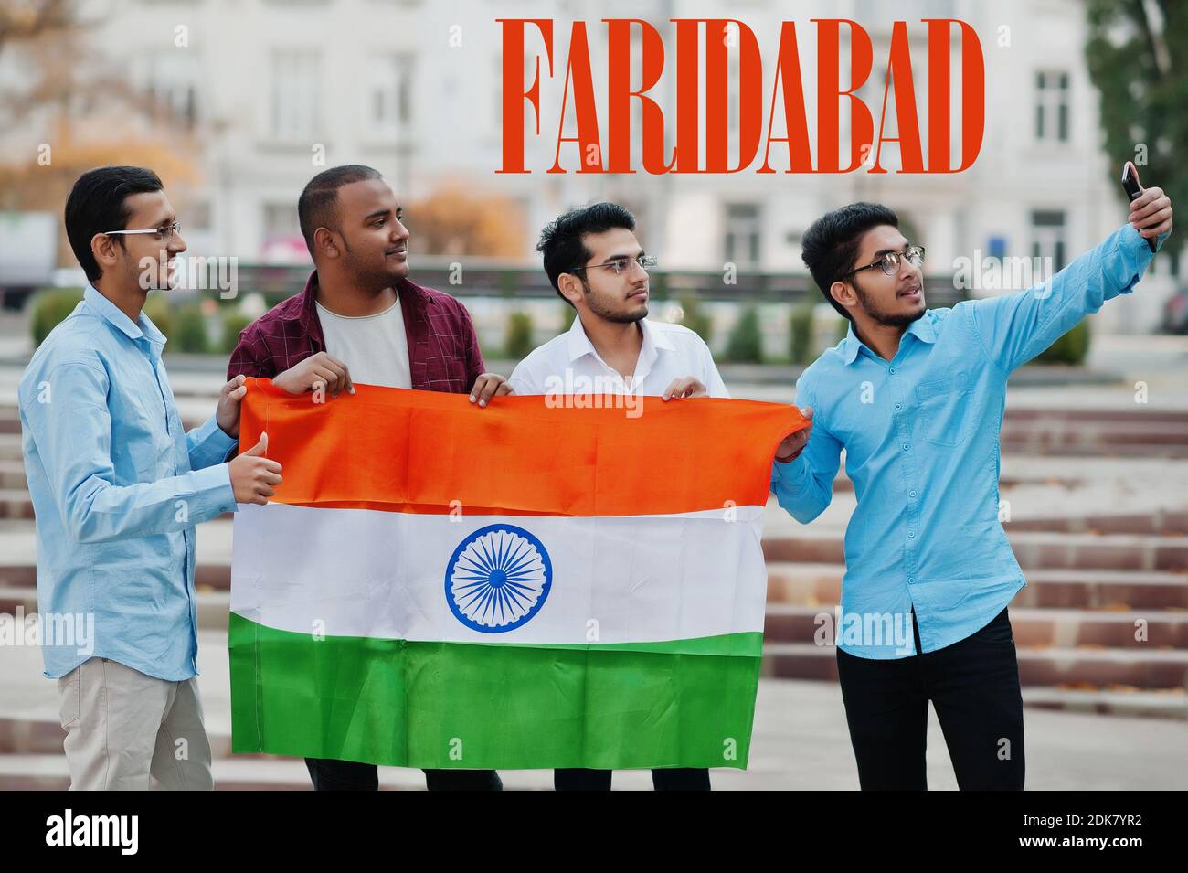 Inscription de la ville de Faridabad. Groupe de quatre amis indiens masculins avec drapeau indien faisant selfie sur téléphone mobile. Concept des plus grandes villes de l'Inde. Banque D'Images