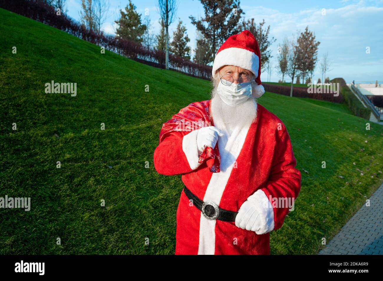 Le portrait en gros plan de l'homme heureux senior en costume du père noël revient à l'appareil photo et sourit. L'humeur du nouvel an. Banque D'Images