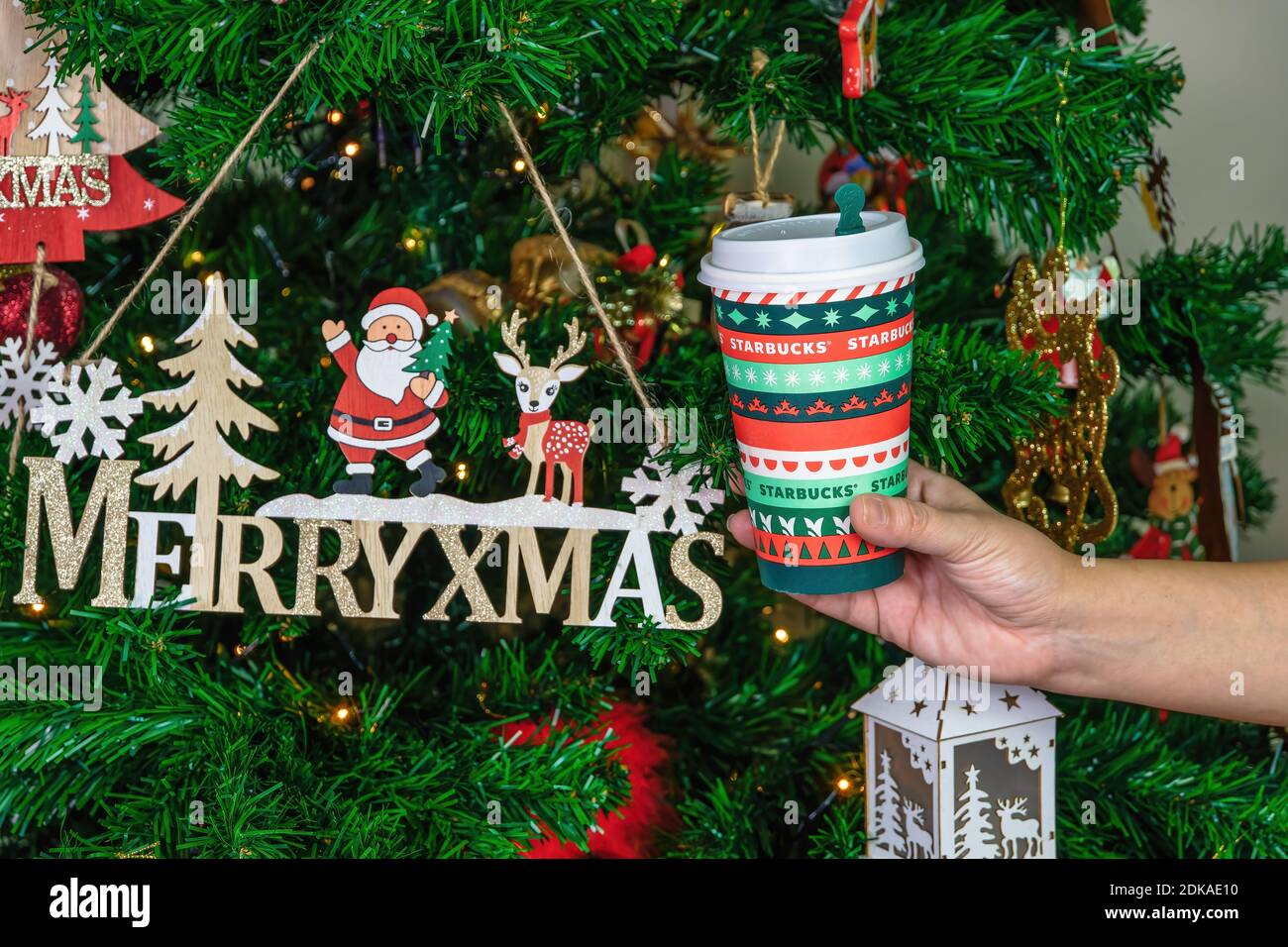 Tasse à café à emporter Starbucks Christmas Blend. Tasse à boisson de saison avec logo de la société avant un arbre illuminé décoré à la main. Banque D'Images