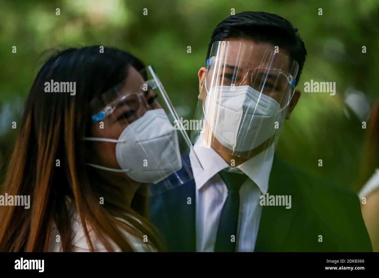 Makati, Philippines. 15 décembre 2020. Un couple portant des masques faciaux est vu lors d'un "mariage masqué de masse" dans un parc de la ville de Makati, aux Philippines, le 15 décembre 2020. Le gouvernement philippin a imposé une politique plus stricte sur la couverture faciale en raison des inquiétudes d'une éventuelle augmentation des cas pendant la période des fêtes. Crédit: Rouelle Umali/Xinhua/Alamy Live News Banque D'Images