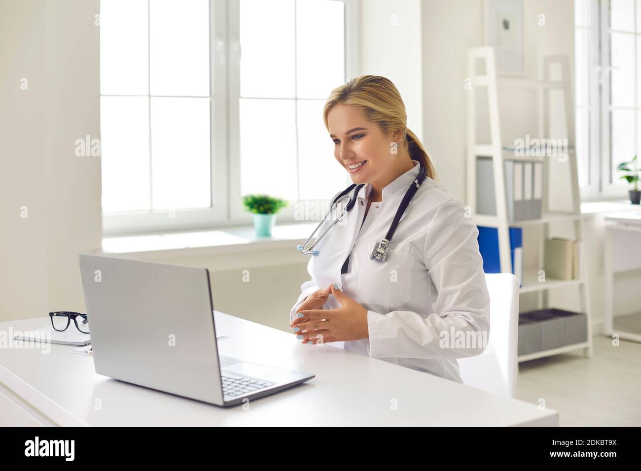 Médecin souriant donnant la consultation de santé au patient pendant l'appel vidéo sur un ordinateur portable moderne Banque D'Images
