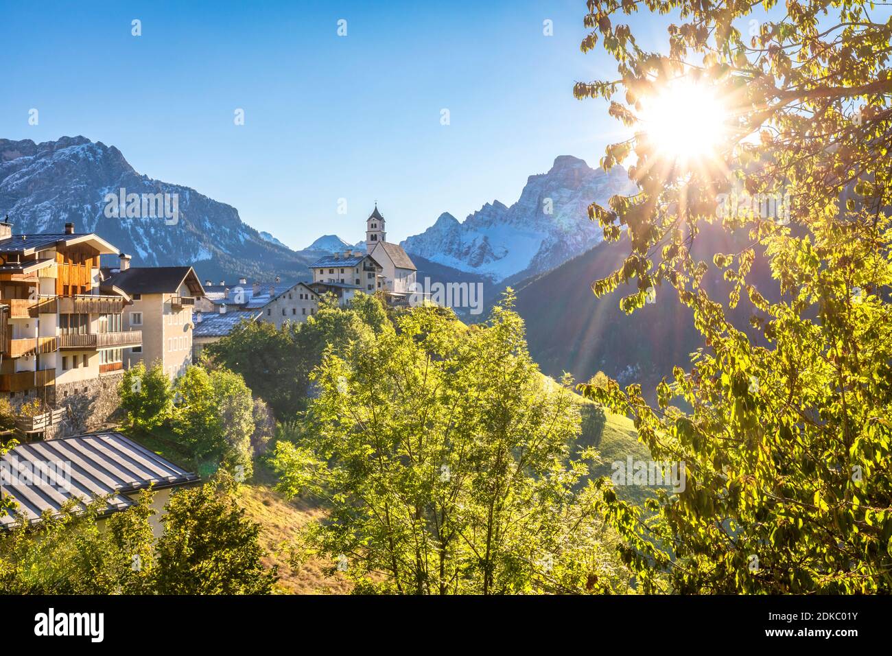 Un aperçu classique du village de Colle Santa Lucia dominé par l'église paroissiale et le Mont Pelmo en arrière-plan, scène d'automne avec le soleil dans le ciel, Agordino, province de Belluno, Vénétie, Italie, Europe Banque D'Images