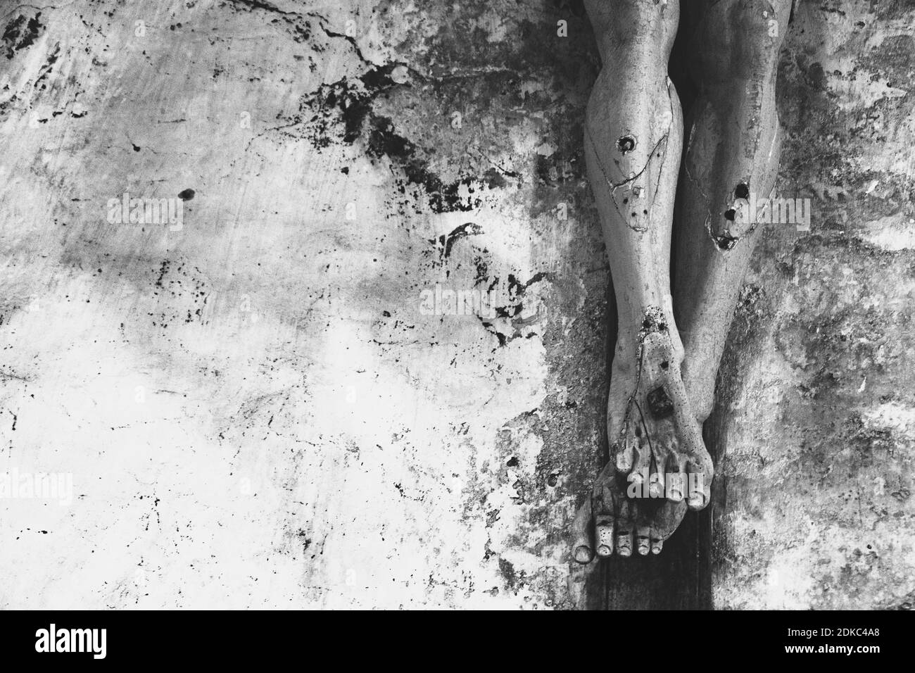 Contexte religieux. Passion, souffrent concept. Gros plan de vieux crucifix en bois avec peinture écaillée contre le mur de pierre grungy dans l'église. Noir blanc Banque D'Images