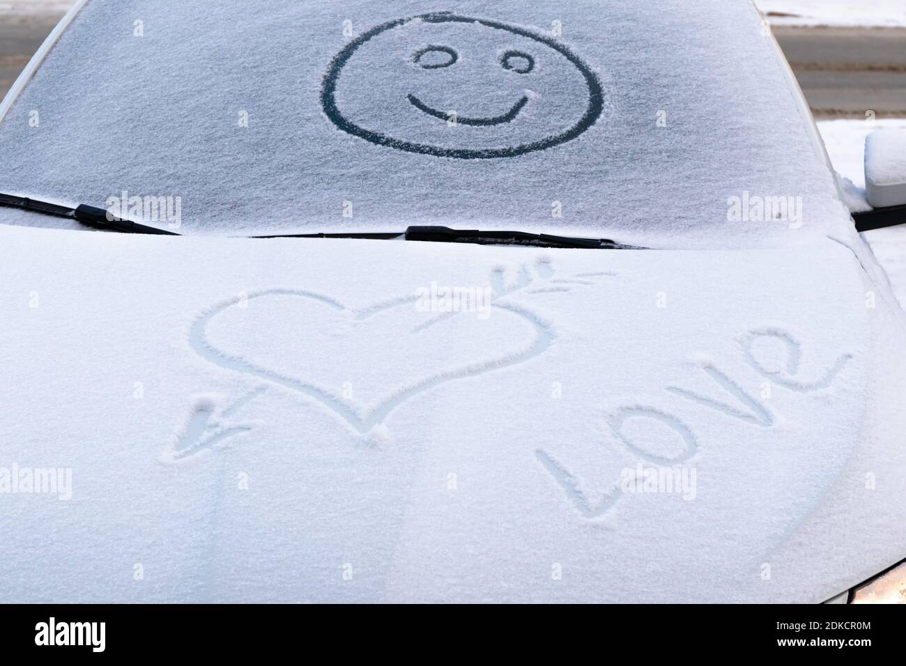 image d'un visage souriant dans la neige sur le pare-brise d'une voiture et forme de coeur sur un hiver glacial Banque D'Images