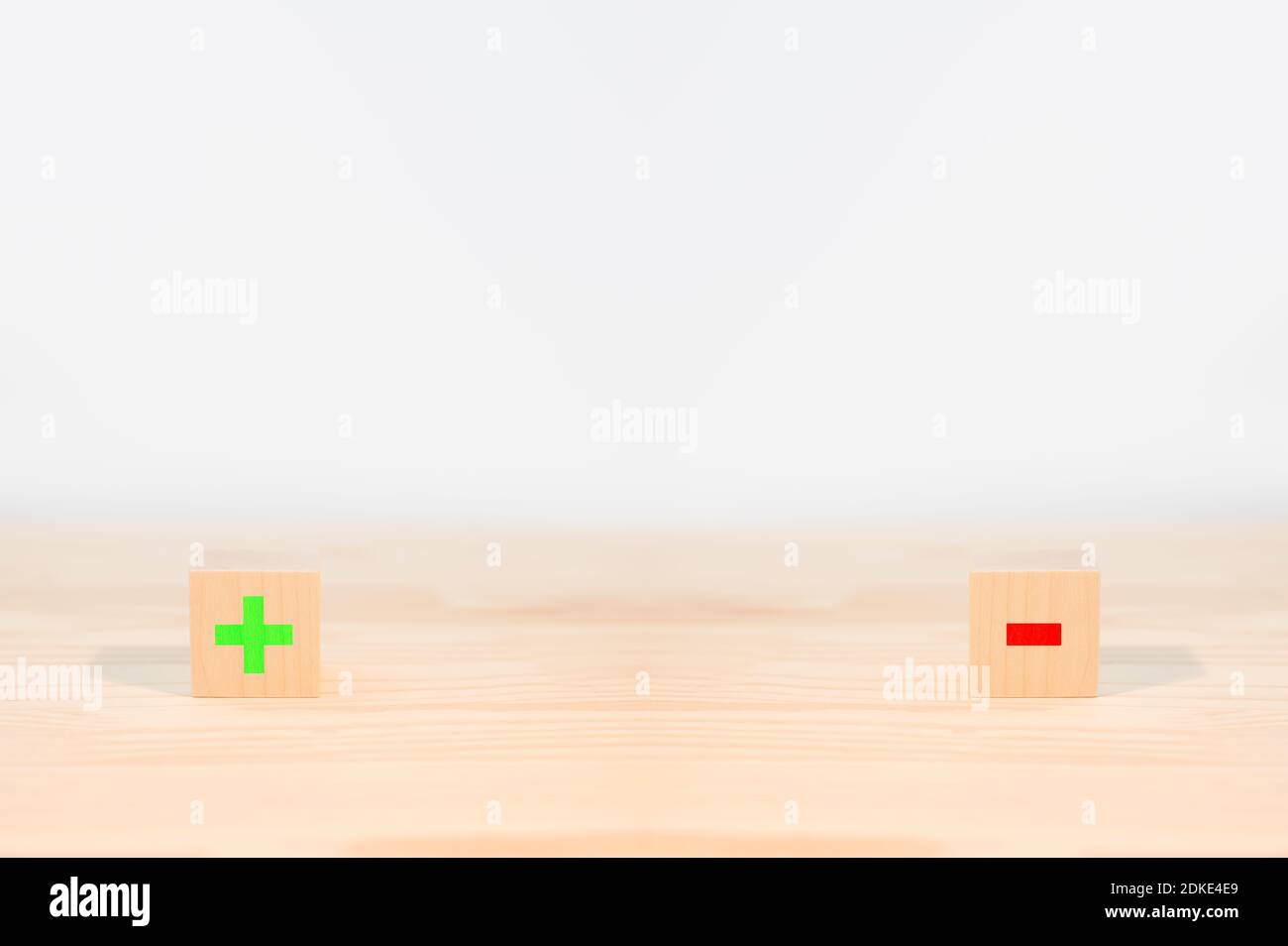 concept de pour et contre. fiche de comparaison pour et contre, deux cubes en bois avec un négatif rouge et un plus vert sur fond blanc. espace de copie Banque D'Images