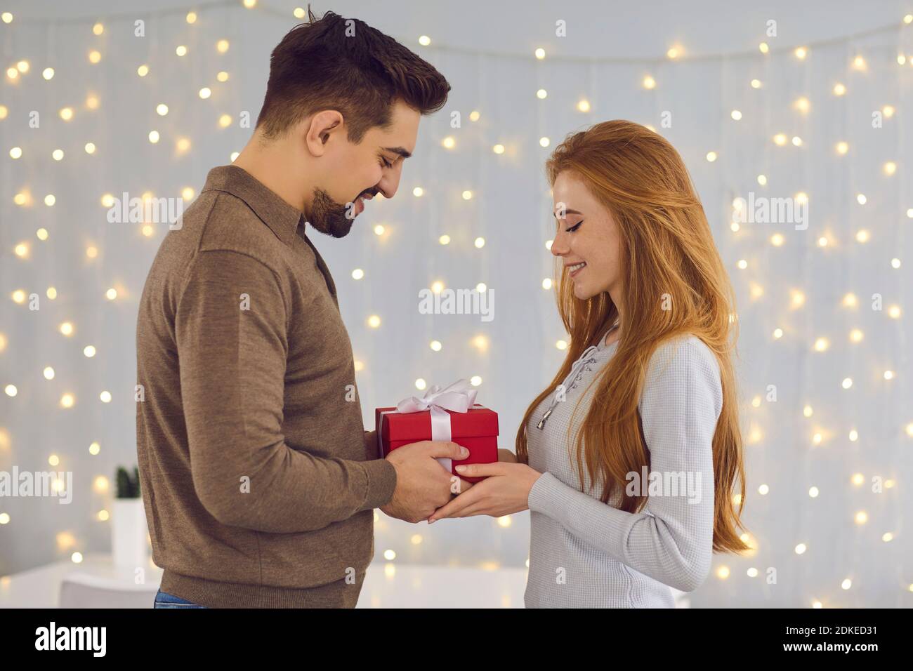 Jeune heureux couple souriant debout et de donner des cadeaux pendant la célébration vacances à la maison Banque D'Images