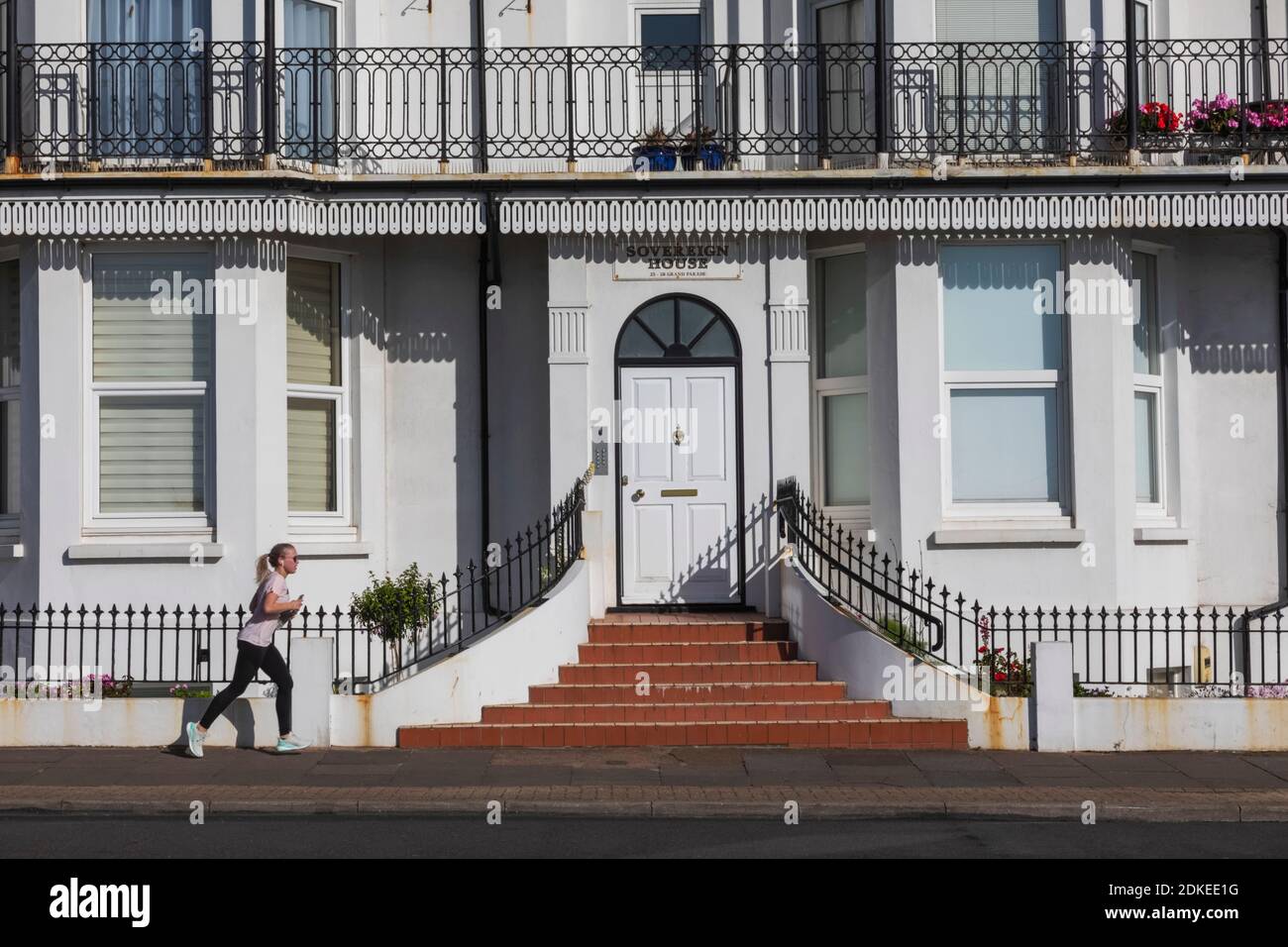 Angleterre, East Sussex, Eastbourne, femme passant devant le bâtiment de bord de mer Banque D'Images