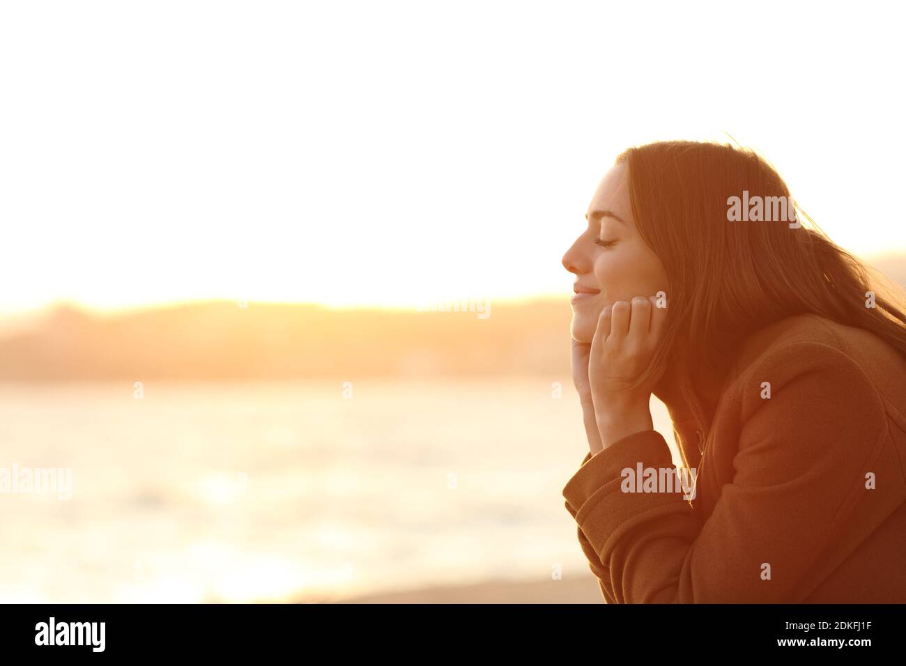 Profil d'une femme avec les yeux fermés au coucher du soleil relaxant l'esprit sur la plage en hiver Banque D'Images