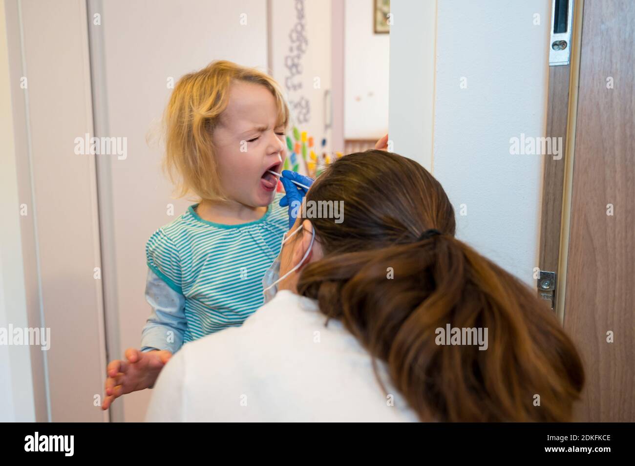 Fille blonde ayant un écouvillon oropharyngé inséré pour la détection de covid 19. Banque D'Images