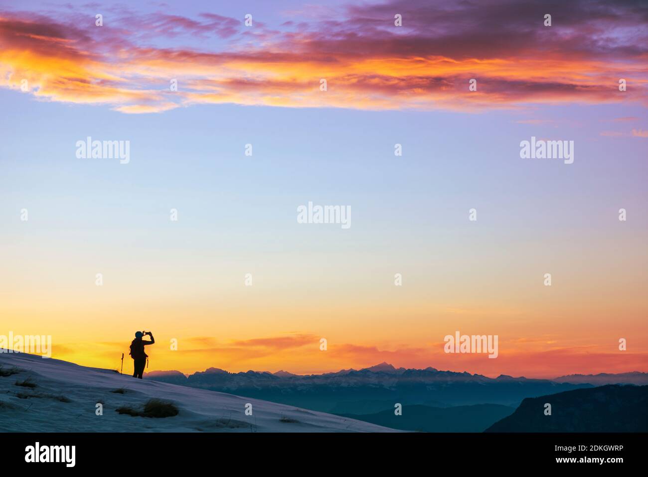Italie, Trentin, col Rolle, Dolomites. Un randonneur solitaire photographie un ciel de coucher de soleil coloré avec un smartphone Banque D'Images