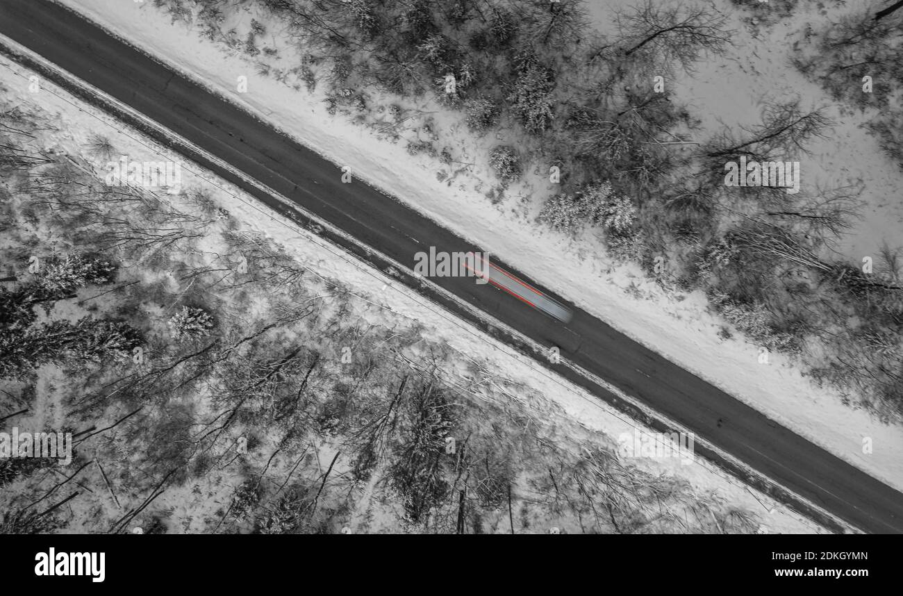 Vue aérienne sur une rue d'hiver bordée de neige, une voiture passe. Banque D'Images
