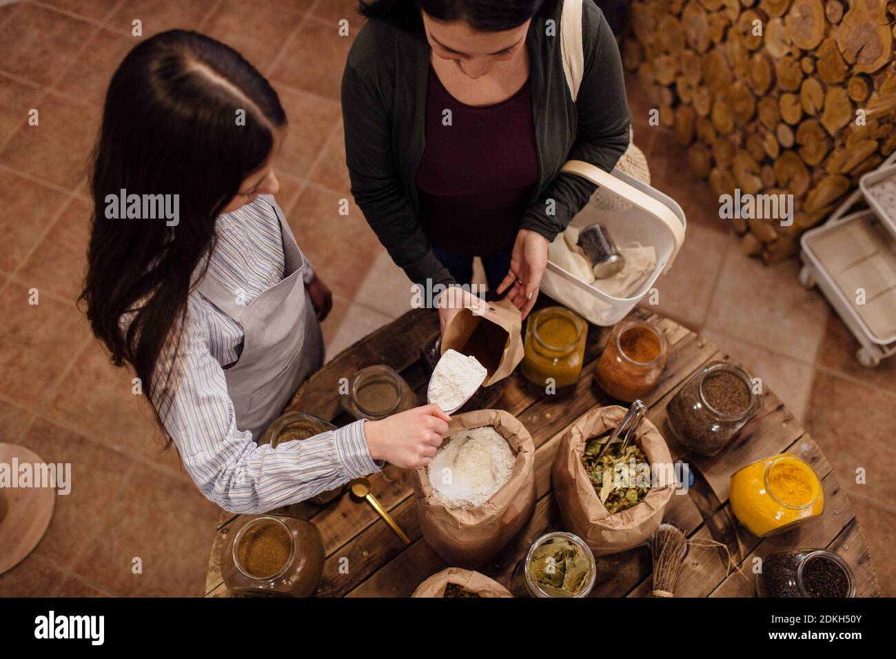 Vue en grand angle de l'assistant d'atelier qui ramasse la farine pour le client dans un magasin d'emballage gratuit. Zéro gaspillage shopping - femme achetant des herbes fraîches et des épices à paquet libre magasin d'alimentation. Banque D'Images