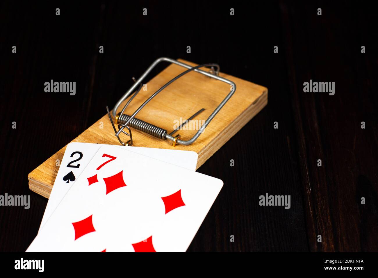 Les mauvaises cartes à jouer se trouvent dans un mousetrap en bois sur un fond en bois sombre. Pas de chance, pas de chance, dans le jeu. Poker perdant. Dépendance de jeu. Banque D'Images