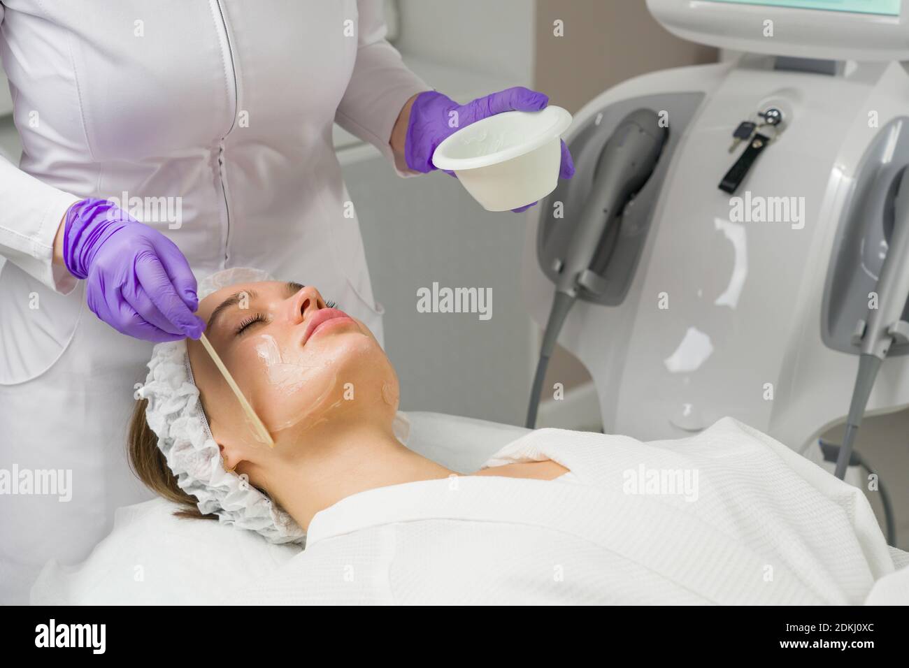 Soin du visage. Un masque est appliqué au visage d'une femme dans une clinique de cosmétologie. Gros plan Banque D'Images